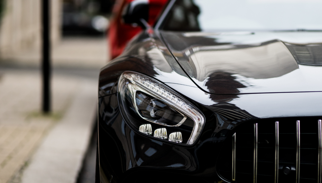 Close-up of a black luxury sports car headlight and grille.