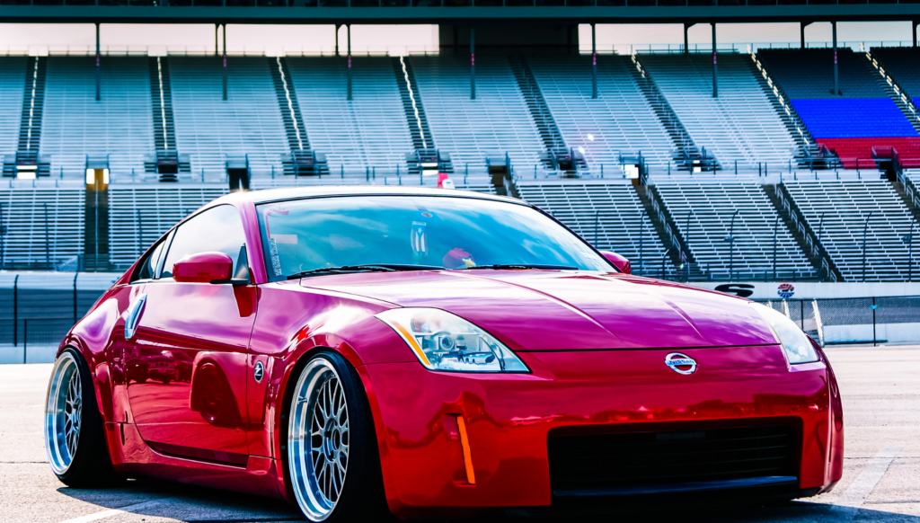 Red sports coupe parked at a racetrack stadium.