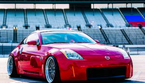 Red sports coupe parked at a racetrack stadium.