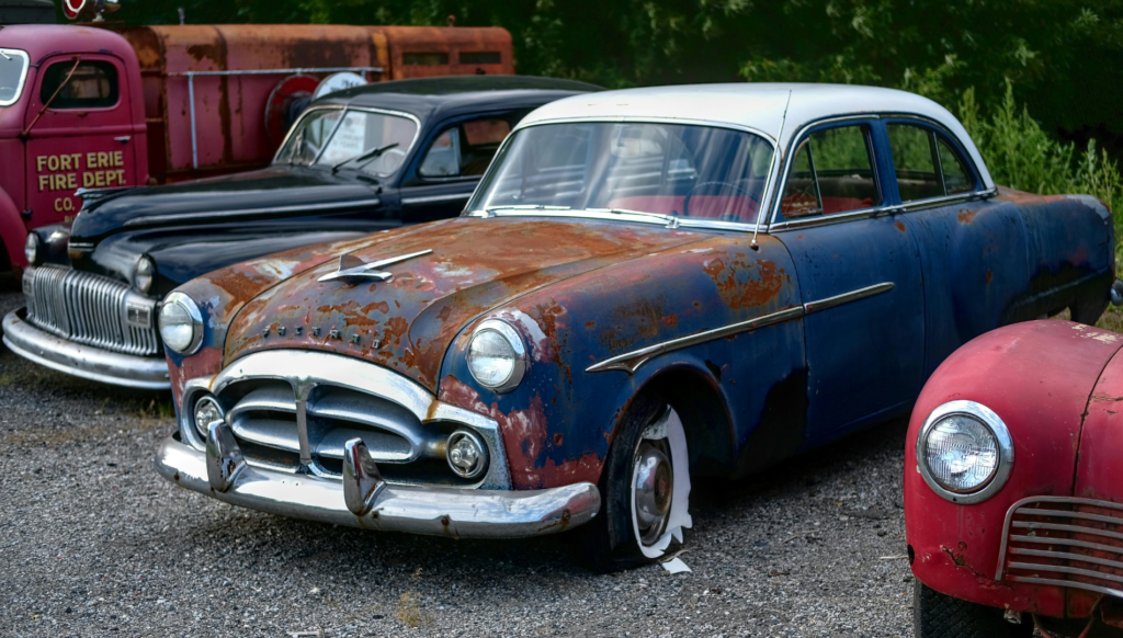 Rusty vintage classic cars parked in an outdoor lot.