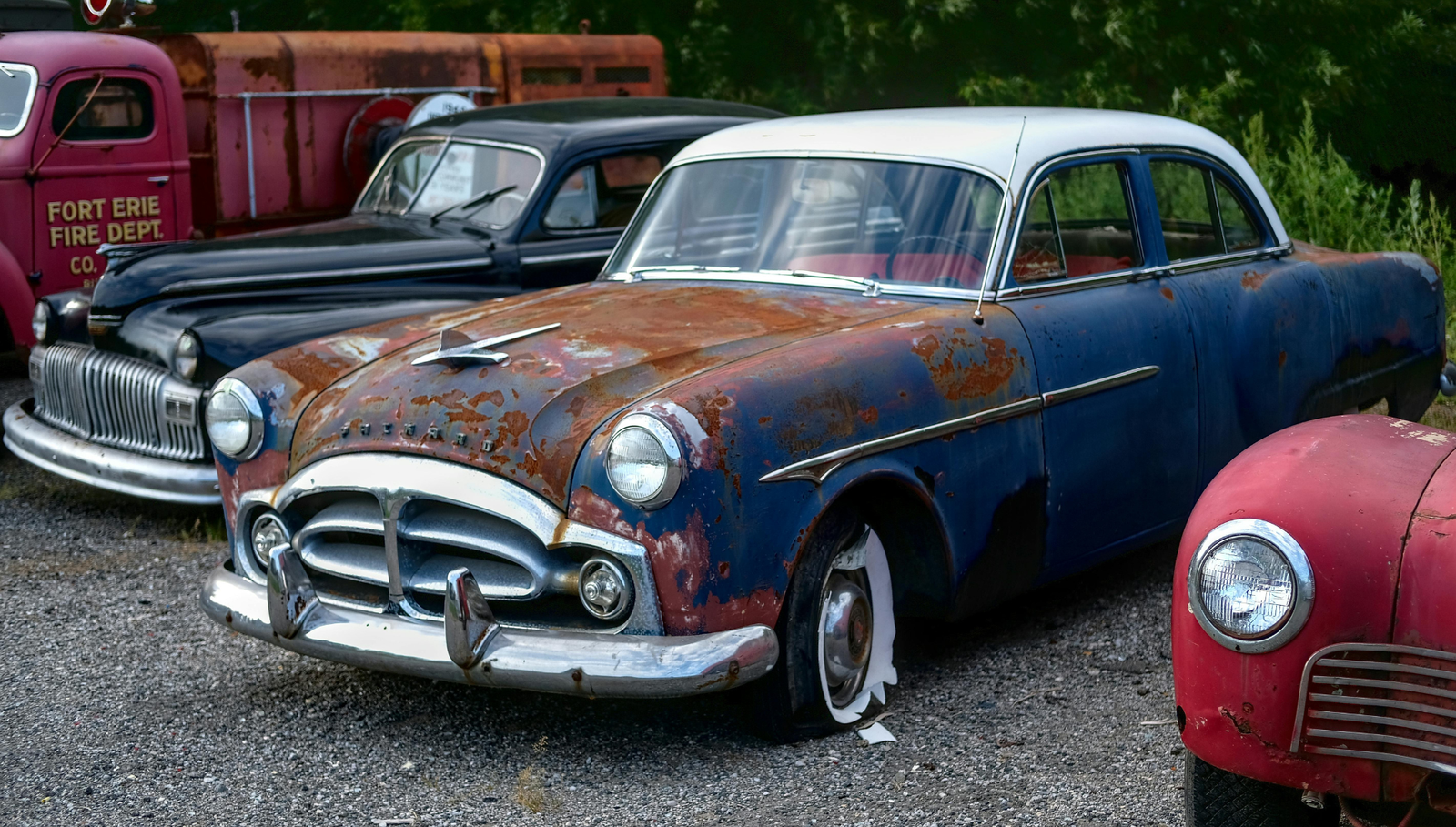Rusty vintage classic cars parked in an outdoor lot.