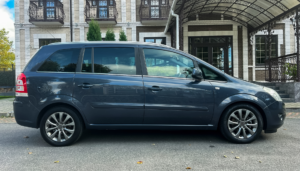 Dark blue family minivan parked in front of a residential building.