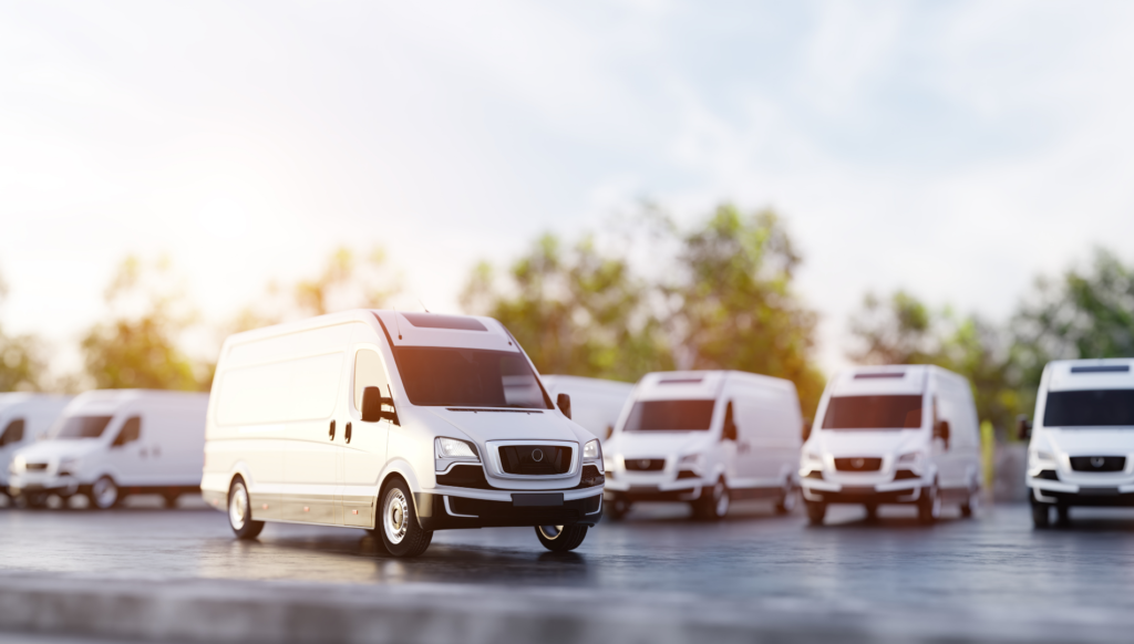 White cargo van parked with delivery fleet in background.