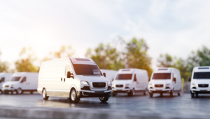 White cargo van parked with delivery fleet in background.