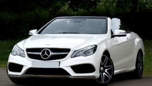 White luxury convertible car parked outdoors near trees.