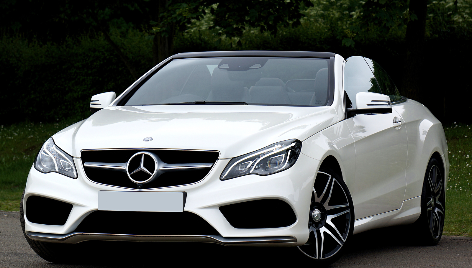 White luxury convertible car parked outdoors near trees.