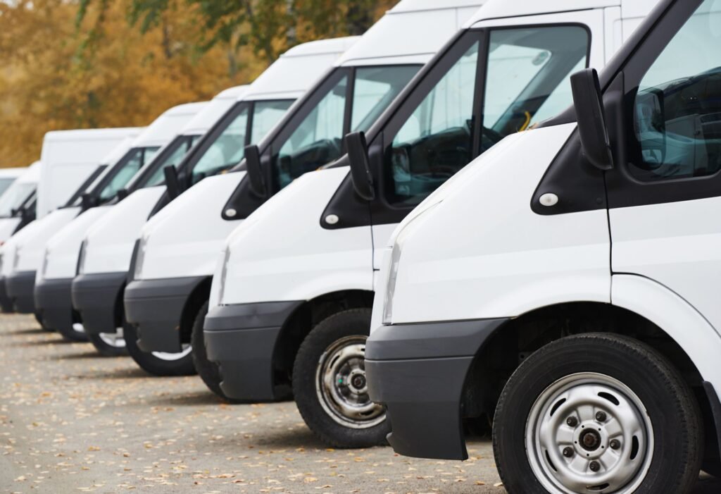 Row of white commercial vans parked in fleet lot
