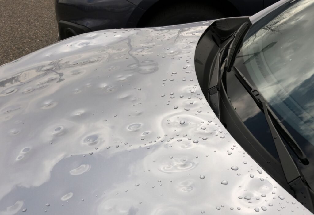 Silver car hood with hail dents
