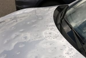 Silver car hood with hail dents