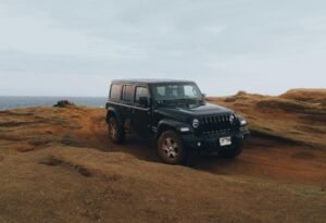 Black Jeep driving off-road near the coast